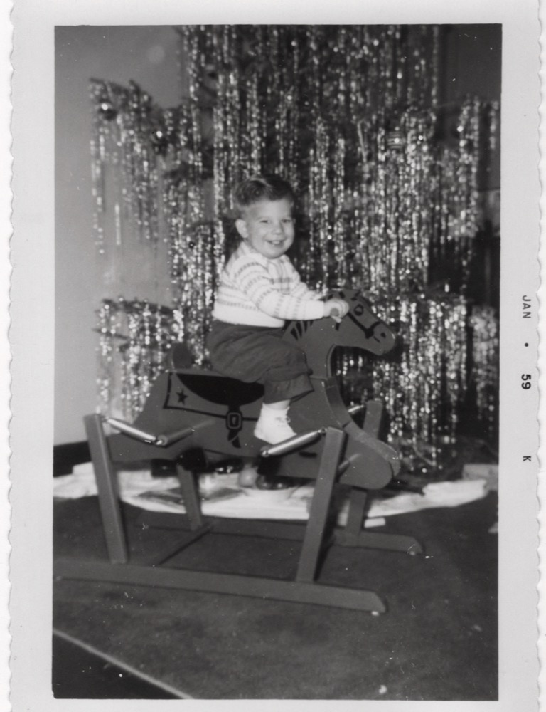Yours truly as an 18-month-old, sitting on a spring mounted rocking horse in front of a Christmast tree in 1959